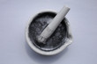 Fine particles of aluminum on the surface of the water in a ceramic mortar with pestle.