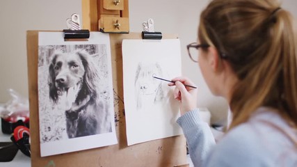 Wall Mural - Female Teenage Artist Sitting At Easel Drawing Picture Of Dog From Photograph In Charcoal