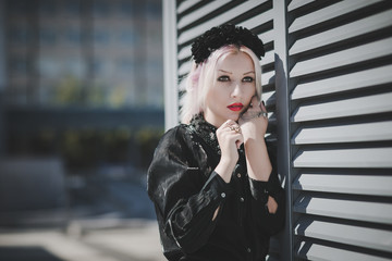 Beautiful girl in black shorts and black shirt look forward stay near metal construction