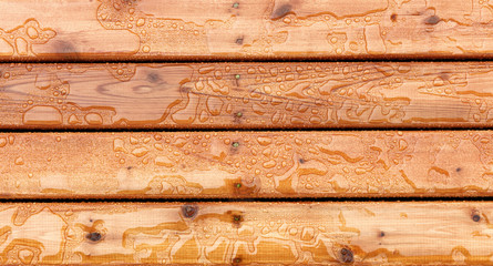 Top view of outdoor wooden stain deck boards with natural rain water on top of them