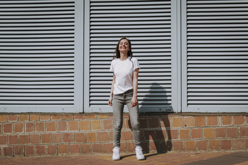 Wall Mural - Pretty smiling hipster girl staying on city view