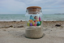 Family Concept With A Composition Of Colored Stones In A Glass Jar On The Beach