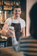 © Yakobchuk Olena - Waist up of friendly barista smiling to the cafe visitor