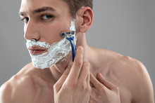 Handsome Young Man Shaving With Disposable Razor