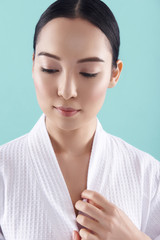 Wall Mural - Portrait of beautiful young Asian woman with pure skin wearing white bathrobe