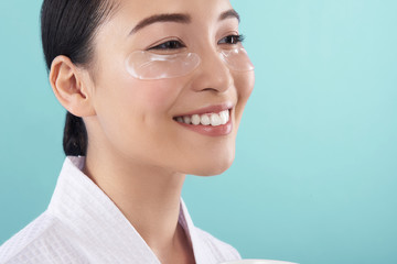 Wall Mural - Close up portrait of Asian lady in white bathrobe smiling in studio