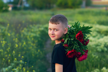 Portrait of a boy with peonies outdoors