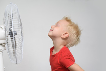 Pretty smiling blond boy in red shirt and closed eyes enjoying the cool air. Summer concept