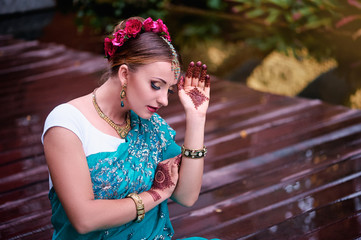 Wall Mural - Beautiful young indian woman in traditional clothing with bridal makeup and jewelry. gorgeous bride traditionally dressed Outdoors in India. Girl bollywood dancer in Sari and henna on hands