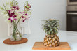 © Annatamila - pineapple and orchid flower on wooden boards in white kitchen
