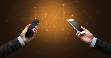 Close up of two hands holding smartphones to each other, wireless connection concept