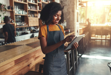 Wall Mural - Female owner using digital tablet in cafe