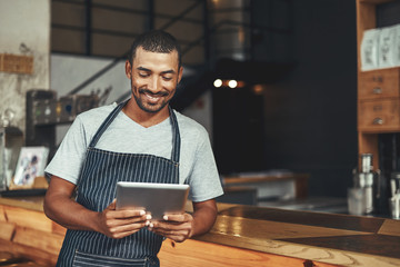 Poster - Smiling male cafe owner looking at digital tablet