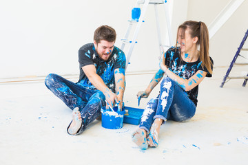 Repair, renovation and people concept - couple going to paint the wall and have fun at the break