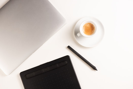 Graphic Designer white work table with computer and coffee.