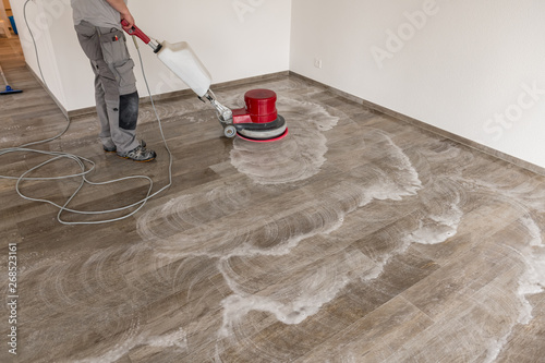 Man cleans the tile floor with a machine in an apartment.