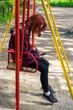 05/17/2009 Russia. St. Petersburg...The girl is sitting on the street, on the swing with the phone.