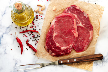 Raw fresh organic marbled meat. Beef, sea salt, pepper and garlic on the table. Rib eye steak (Ribeye Black Angus) to prepare a delicious dinner.  Selective focus