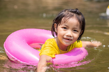 Little Asian girl in pool ring swimming in  river