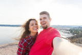 Fototapeta Do akwarium - Travel, vacation and holiday concept - Beautiful couple having fun, taking selfie, crazy emotional faces and laughing.