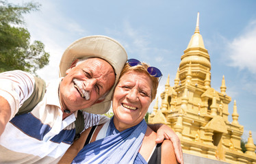 senior couple taking selfie at golden temple in ko samui - happy retired people traveling to thailan