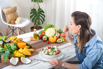 Young and happy woman eating salad at the table