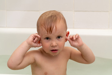 Little boy 3 years old bathes in the bath