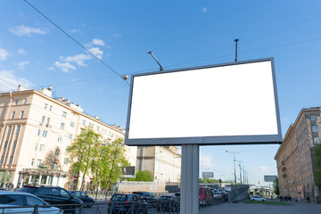 Blank white billboard against the blue sky near the road in the city