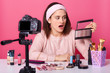 © sementsova321 - Surprised emotional lady looking at palette of colorful eyeshadow, holding it with one hand, opening mouth and eyes widely, sitting at table around other cosmetic products. Beauty bloggering concept.