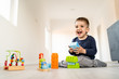 © Miljan Živković - Small boy playing with little brick block toys at home on the floor smiling