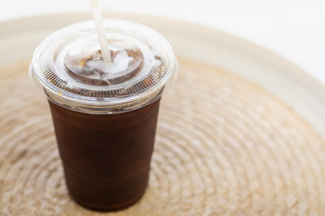 Wall Mural - Close up of take away plastic cup of iced black coffee (Americano) on round table.