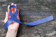 © Chinnapong - Colorectal or Colon cancer awareness dark blue ribbon on helping hand on old aged woo