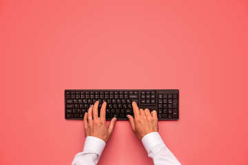 Wall Mural - Typing on black computer keyboard over pink background