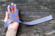 © Chinnapong - Esophageal cancer awareness Periwinkle color ribbon on human hand with aged wood background