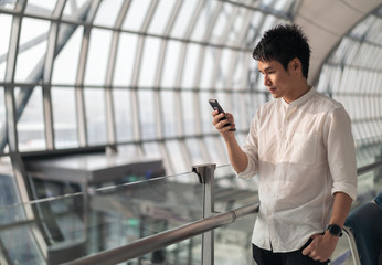 Wall Mural - man waiting for flight and using smart phone in airport