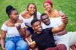 © yurakrasil - group of five friends female and male taking selfie on camera smartphone and having fun outdoors lifestyle near lake,eating burger picnic in the park
