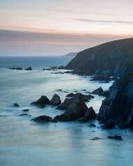 Wall Mural - stunning sunset landscape image of westcombe beach in devon england with jagged rocks on beach and s