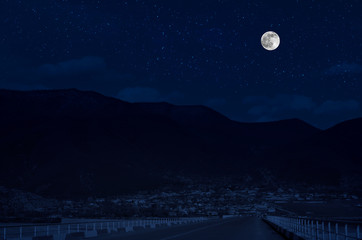 Wall Mural - mountain road through the forest on a full moon night. scenic night landscape of country road at nig