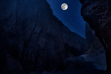 Wall Mural - mountain road through the forest on a full moon night. scenic night landscape of country road at nig