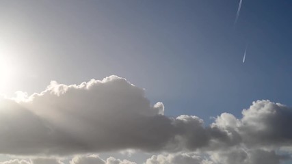 Wall Mural - Time-lapse of clouds, sun rays and beams, airplanes and birds moving through a foggy, misty sky.