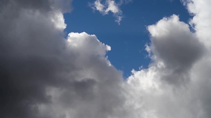 Wall Mural - Dynamic, fluffy, fast clouds moving through a misty colorful blue sky
