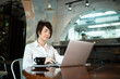 © toxicoz - A middle-aged woman sits in a cafe, drinks coffee and works at a computer. Woman holding a phone