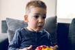 © Miljan Živković - Portrait of a little small boy eating unhealthy snacks corn peanut flips at home