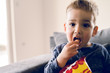 © Miljan Živković - Portrait of a little small boy eating unhealthy snacks corn peanut flips at home