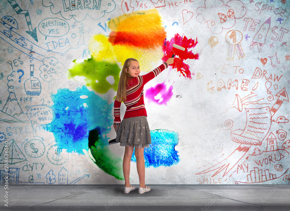 Little girl standing in front of the wall and paints with the bright ...