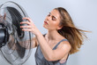 © Svetlana Radayeva - Young woman enjoying cool wind from electric fan