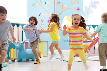 group of happy children of boys and girls run in day care. kids playing in kindergarten