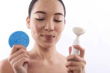 Asian lady smiling and holding two cosmetic sponges