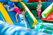 Child jumping on colorful playground trampoline. Kids jump in inflatable bounce castle on kindergarten birthday party Activity and play center for young child. Little girl playing outdoors in summer
