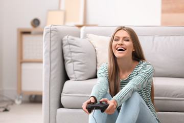 Wall Mural - Emotional young woman playing video games at home